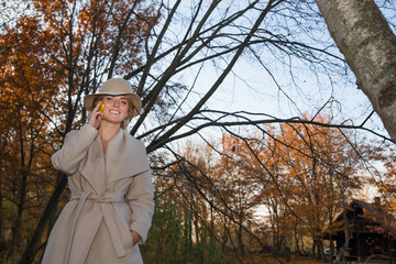 beautiful woman in a coat hat and a white dress for a walk in an autumn park or forest.