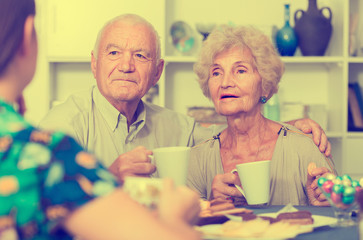 Happy mature couple drinking tea with female guest