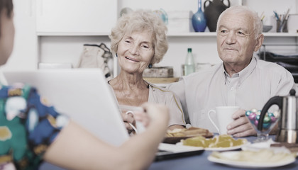 Young woman showing elderly couple something on laptop