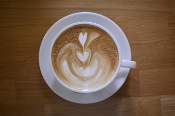 coffee latte art foam in white cup on wooden table, top view