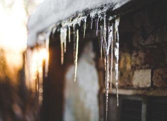 Beautiful Photo Winter, icicles hanging from the roof, sunset - obrazy, fototapety, plakaty