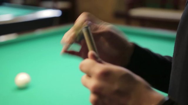 the guy rubs the cue for playing Billiards