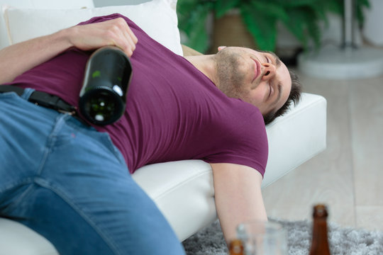 man sleeping holding an alcohol bottle
