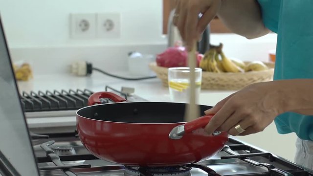 Woman standing in the kitchen and cooking dish, steadycam shot
