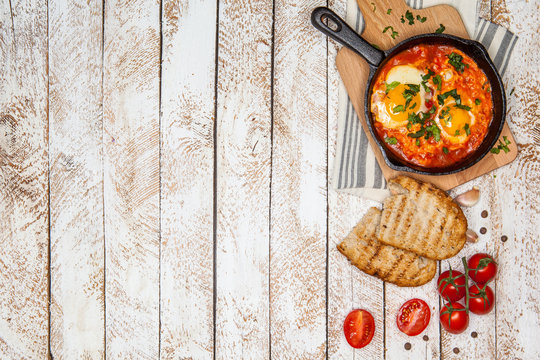 Breakfast. Shakshuka with bread in pan on a wooden background in the Turkish Middle eastern traditional dishes. Top view. Space for text. Middle eastern style breakfast or lunch