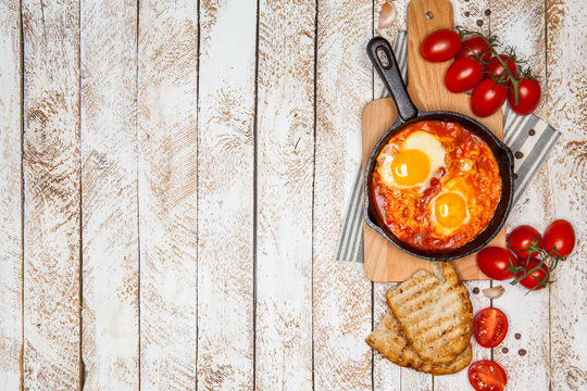 Breakfast. Shakshuka with bread in pan on a wooden background. Top view. Space for text. Middle eastern style breakfast or lunch