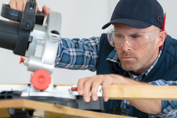 construction worker using slider compound mitre saw