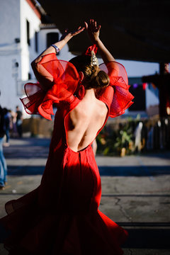 Woman from her back dancing sevillanas with a red regional costume in Granada, Spain.