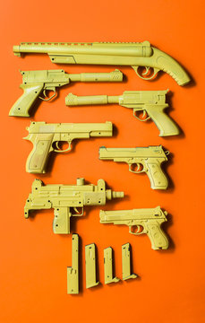 Different kind of firearm weapon in yellow color on orange background .