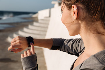 Close-up photo of happy sport woman checking time after workout, seaside outdoor