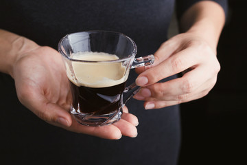 Woman holding espresso coffee in glass cup