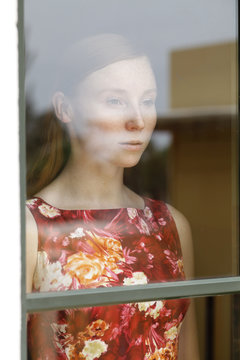 young woman in red dress looking through window