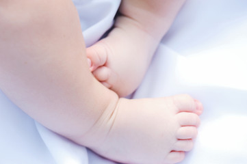 Fototapeta na wymiar The child feet on the white sheet. indoor.Concept newborn.
