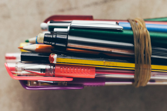 Back to school. Overhead of pens and pencils together with a rubber band.