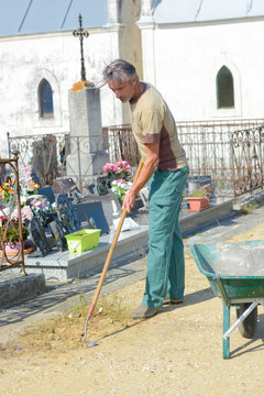 Man raking stones in graveyard