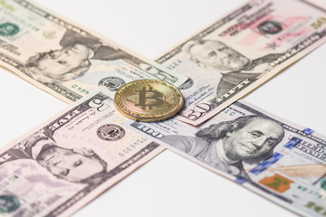 5, 20, 50 and 100 US dollars laid out with a cross with gold bitcoin in the center.