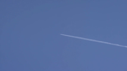 A plane is flying in the sky. Airplane aviation airport contrail the clouds. White airliner transports passengers while it pulling white contrails in dark blue cloudy sky. Airplanes in blue sky with