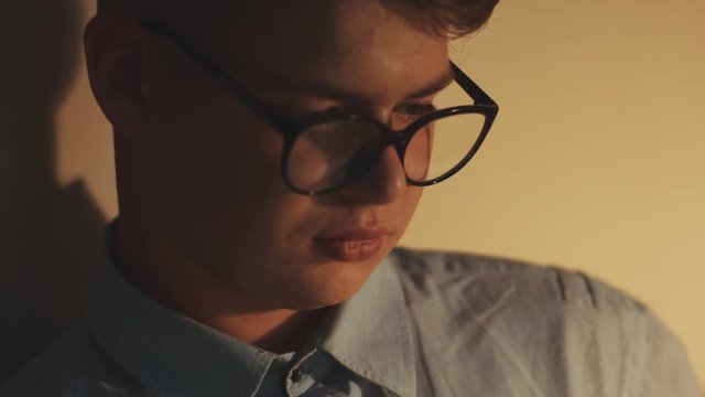 Closeup portrait of young geek guy businessman it programmer software developer lawyer manager designer in modern round glasses sitting in office looking in the screen and analysing information using
