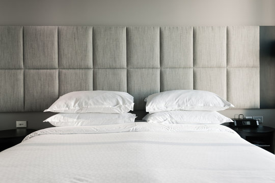 modern bed with white sheet and grey headboard