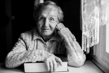 Black and white contrast portrait of an elderly woman sitting with a book.