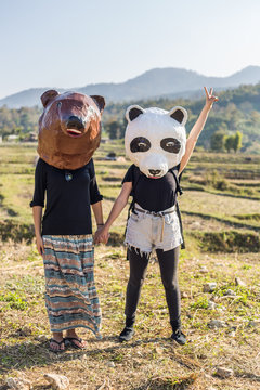Two friends holding hands and wearing bear and panda mask