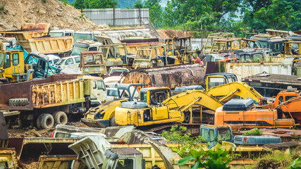 junkyard full of colorful heavy machinery in the valley surrounded by vegetation