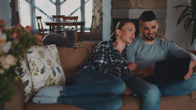 Family home concept, flower parallax portrait of happy young couple people - man, woman and cat sitting in house flat atmosphere and surfing at internet using laptop computer tablet phablet pad