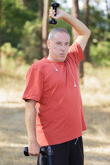 Fototapeta premium mature man exercising with dumbbell at park