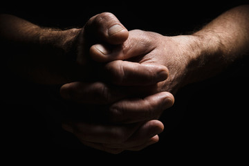 Hands of an elderly man's palms together, thought about problems, with dramatic lighting