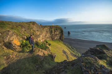 Fototapeta na wymiar Tourist standing near lighthouse on the cliff in Cape Dyrholaey, Iceland