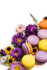 Colorful macarons, flowers and leaves on a white background. Colorful french dessert with fresh flowers. Autumn concept