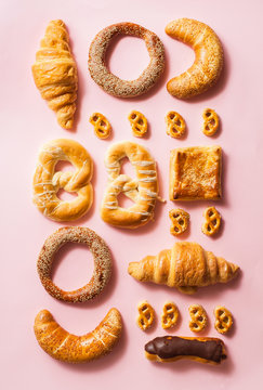 Miscellaneous types of pastry arranged in order on pink backgorund.