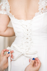Obraz na płótnie Canvas Wedding. Bridesmaid helps the bride to wear dress