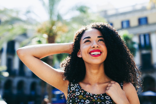Young latin afro woman smiling standing in the city on a sunny day.