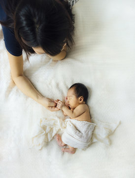 Asian newborn baby and mother, holding hands in white background