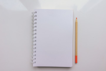 Open Notepad with a blank sheet of paper and a pencil on a white background. Top view