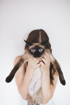 Young woman holding siamese cat