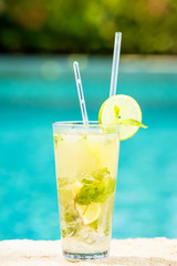 Mojito cocktail at the edge of a resort pool.  Concept of luxury vacation