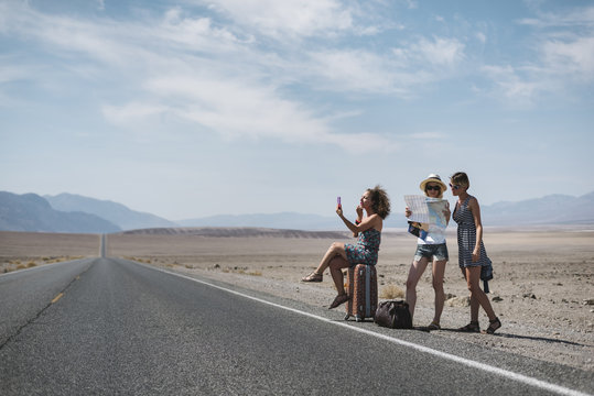 Three young women hitch-hiking in the desert