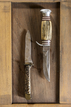 Two old hunting knives on a wooden board