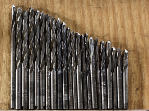 Different drill bits on wooden background