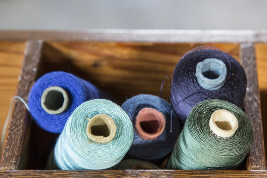 Blue and green colored yarn rolls in wooden box