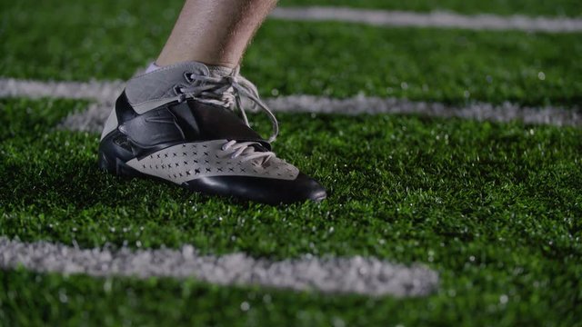 Close up of a football player planting his foot on a spot in the turf