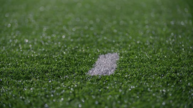 Close up of cleats running by a hash mark on a turf football field 