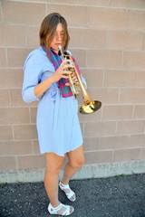 Female jazz trumpet player blowing her horn outside.