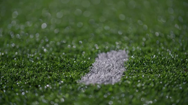 Close up of cleats running by a hash mark on a turf football field 