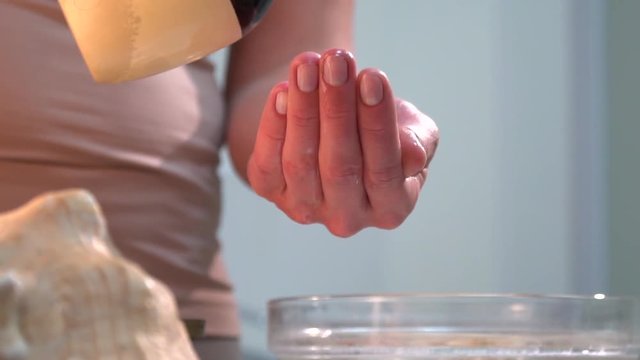 Refocus from seashells on a bottle of oil that a woman takes a massage therapist