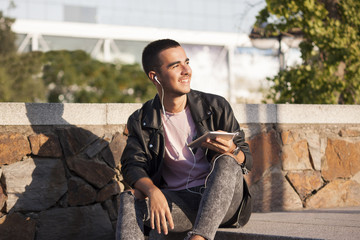 Obraz premium Young man excited listening music at the tablet on the stairs