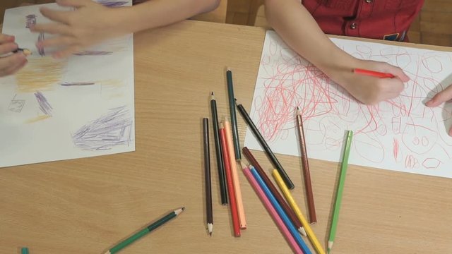 Close-up of hands of unidentified little children drawing pictures using multicolored pencils in kindergarten