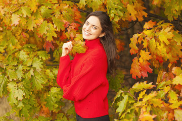 Smiling girl in the public park during the autumn. Colorful season.